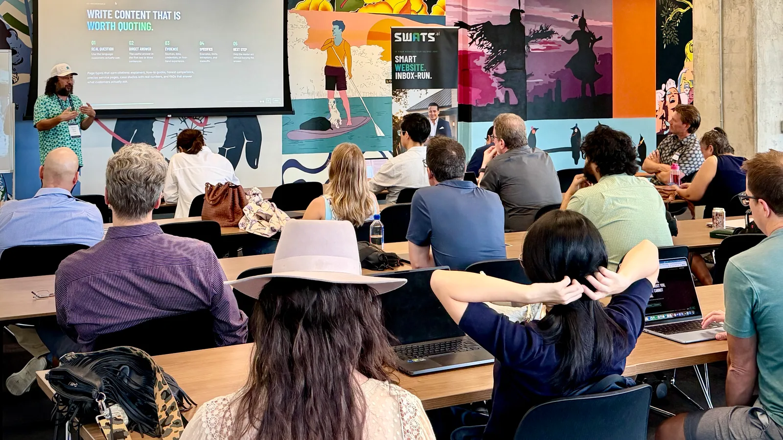 Jenaro Diaz hablando en The Austin Forum on Technology & Society, con una diapositiva que dice “Write content that is worth quoting” detrás de él y un banner de SWATS junto al escenario, frente a una sala llena.