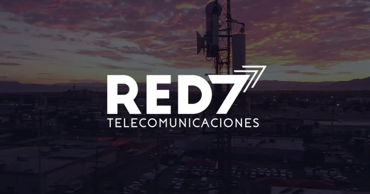 El logo de Red 7 Telecomunicaciones sobre una de sus torres de red al atardecer.